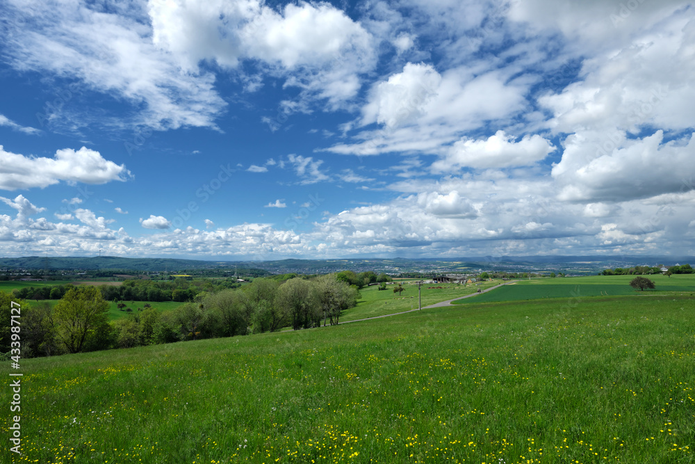 Naklejka premium Panorama von Landschaft mit Blick über grüne Wiesen und Bäume und Büsche vom Westerwald aus und Koblenz und die Eifel im Hintergrund - Stockfoto