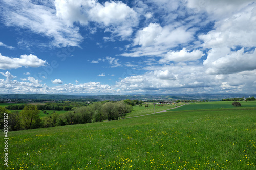 Panorama von Landschaft mit Blick   ber gr  ne Wiesen und B  ume und B  sche vom Westerwald aus und Koblenz und die Eifel im Hintergrund - Stockfoto