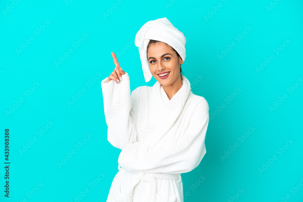 Young woman in a bathrobe over isolated blue background pointing up a great idea Young woman in a bathrobe over isolated blue background pointing up a great idea