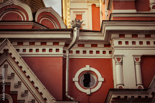 A building with a white-red relief ornament and a chimney with a crown.