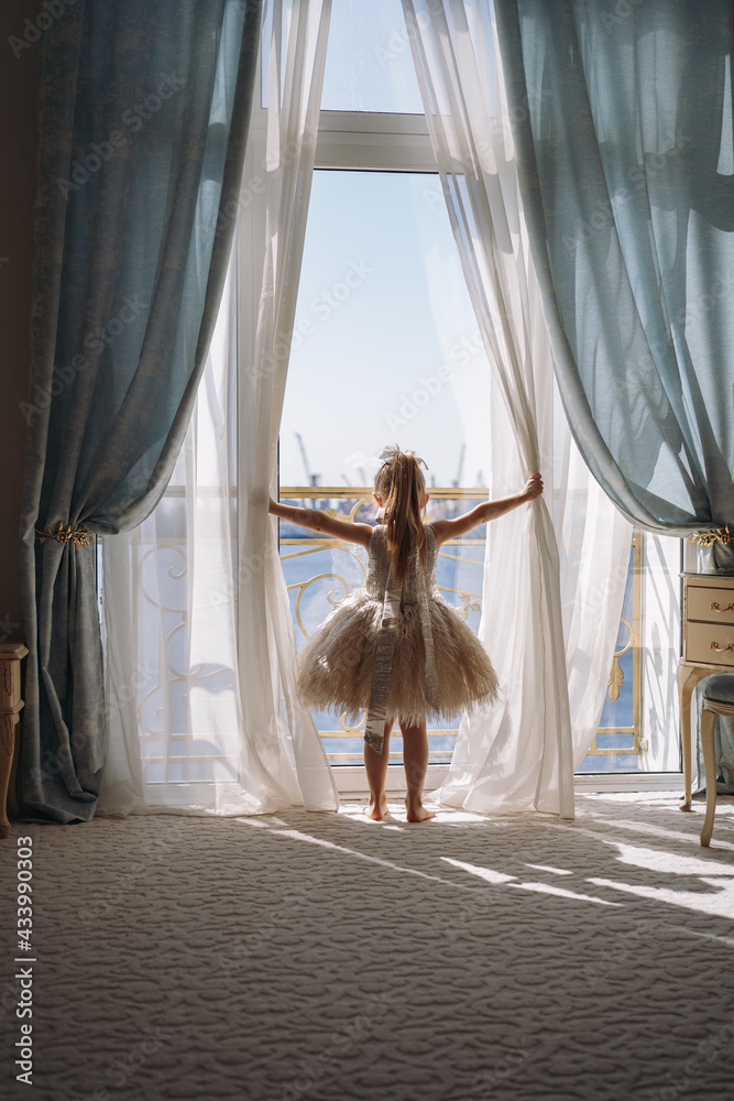 Back view of little girl in white dance dress standing by the