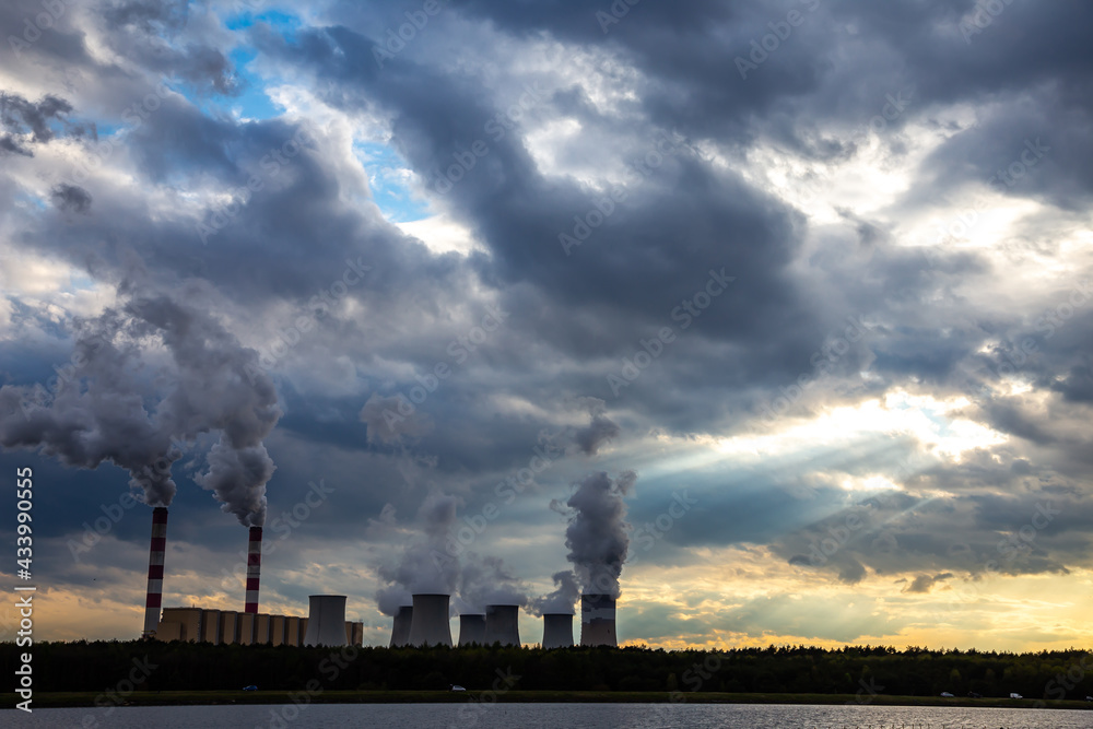 A view of the smoking chimneys of a coal-fired power plant against the backdrop of a dramatic sky with clouds. The photo was taken in natural daylight. A view of the smoking chimneys of a coal-fired power plant against the backdrop of a dramatic sky with clouds. The photo was taken in natural daylight.