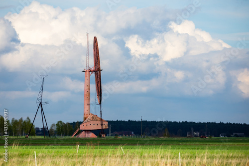 An old, closed wind farm standing alone in a field. Object against the sky with tiny clouds. The photo was taken in natural daylight.