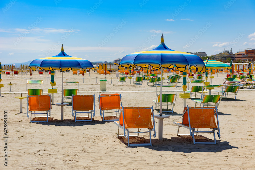Bright, colorful umbrellas and sun loungers on the beach in Rimini, Italy.