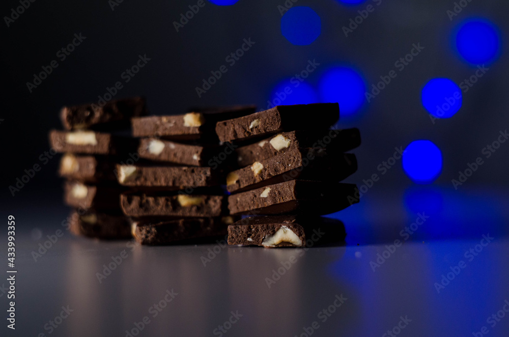 Naklejka premium milk chocolate with nuts, garland in the background