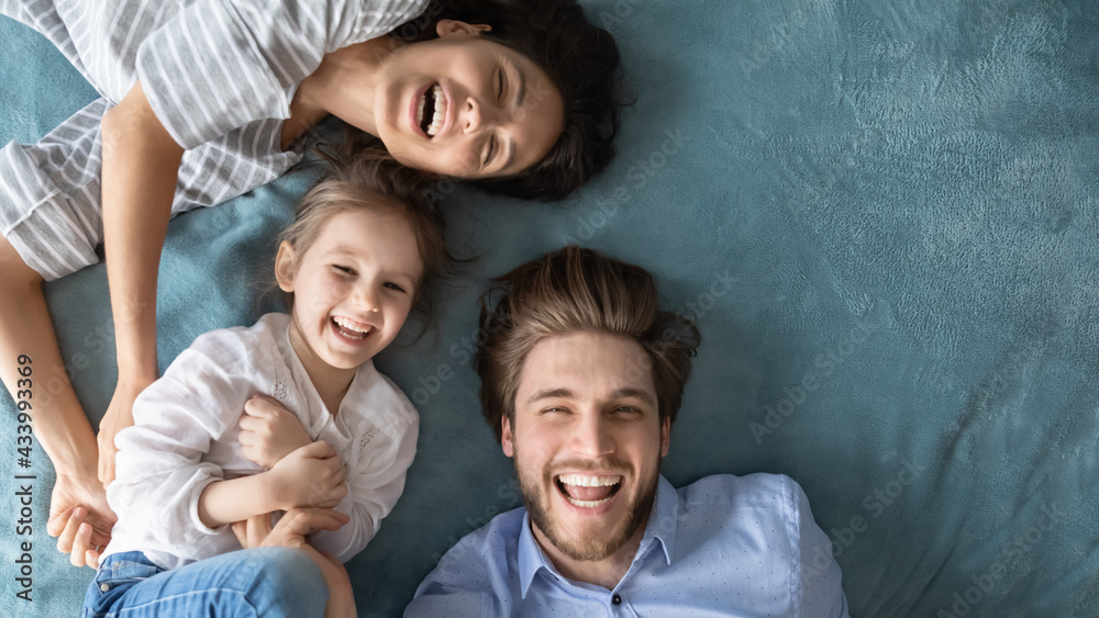 Self-portrait picture of happy young parents with little daughter play together at home on family weekend. Smiling Caucasian mom and dad have fun with small girl child together. Parenthood concept.