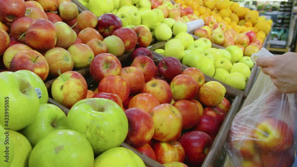 A woman is buying apples at the supermarket. A customer at a grocery store or market A woman is buying apples at the supermarket. A customer at a grocery store or market