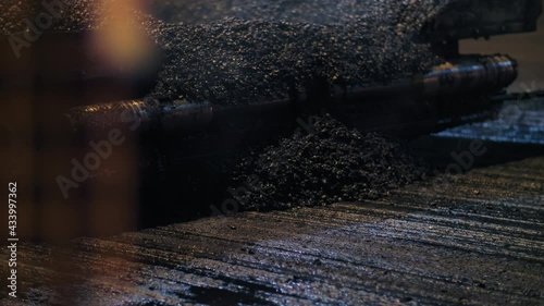 Close-up of fresh hot asphalt mix. An asphalt paver is laying asphalt mix on the road. Road repair, new road construction.