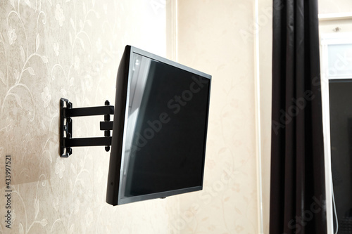 Swivel TV bracket LED display. Side view. X-shaped red fasteners. Black color. Multiplanar. Hangs on a wall. Reliable and comfortable fastening. Childproof and rollover protection. Metallic equipment photo