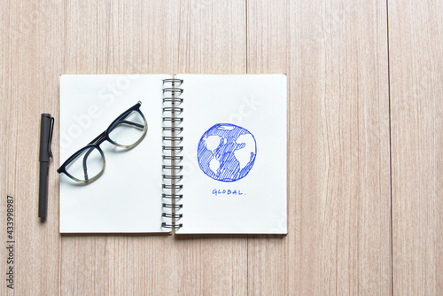 Open notebook with a double page blank space with blue pen global sketch with a fountain pen and glasses for your text on a wooden desk with copy space