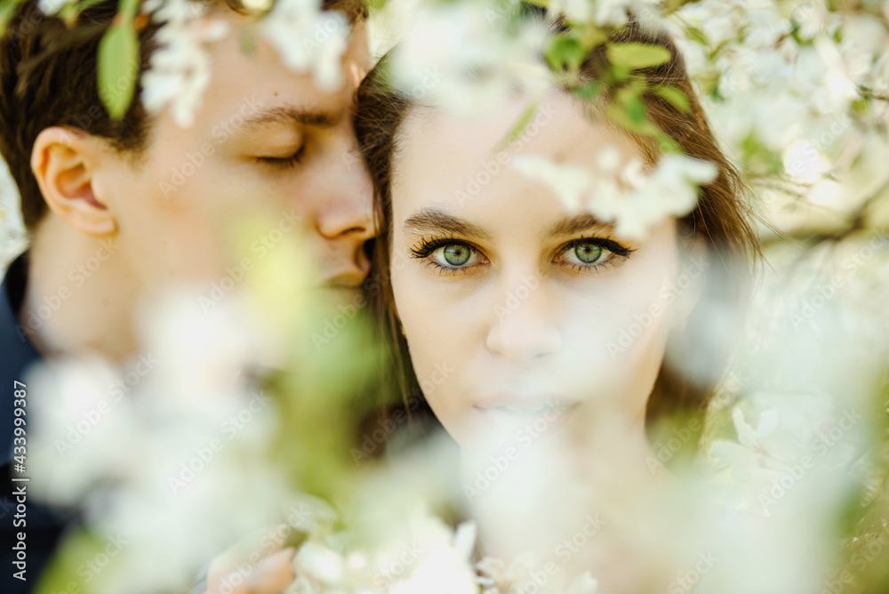 Fototapeta premium young beautiful couple hugging in a blossoming cherry flowers tree.