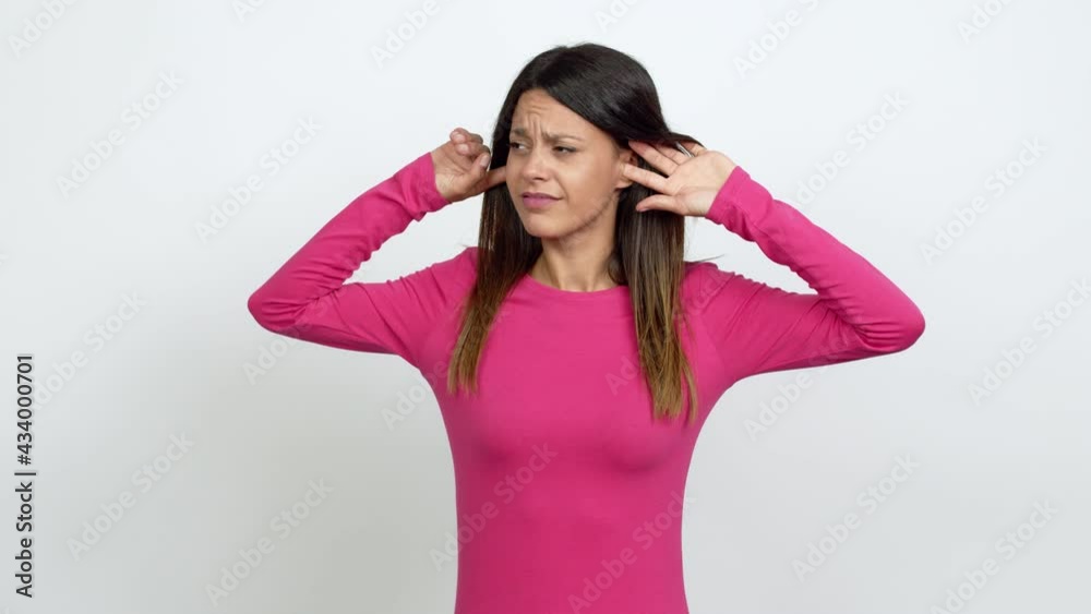 Young woman covering both ears with hands. Frustrated expression over isolated background Young woman covering both ears with hands. Frustrated expression over isolated background