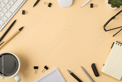 Top view photo of white keyboard mouse plant glasses planner cup pens and binders on isolated beige background with copyspace in the middle