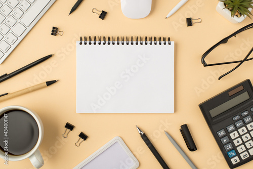 Top view photo of organizer in the middle keyboard mouse pens binders cup glasses plant and calculator on isolated beige background with blank space