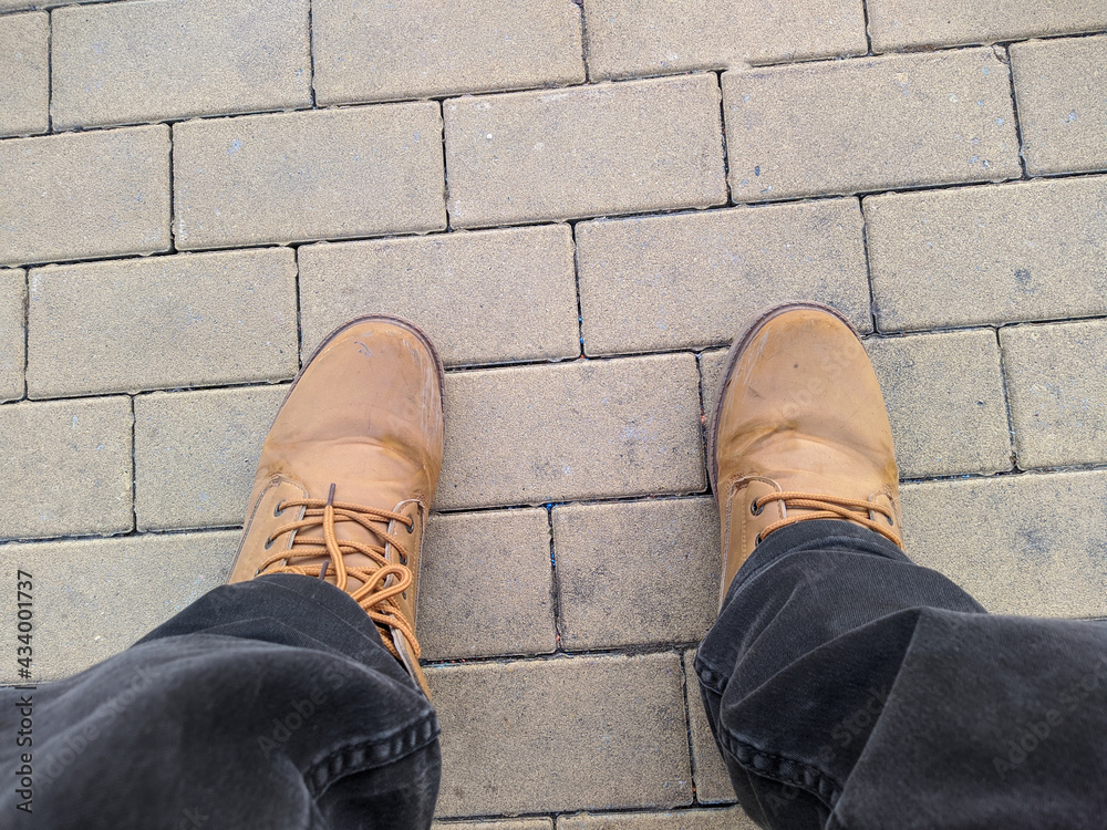 legs in brown boots on the sidewalk in the park first person view legs in brown boots on the sidewalk in the park first person view