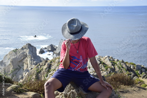 Child in hat on a cliff over the sea