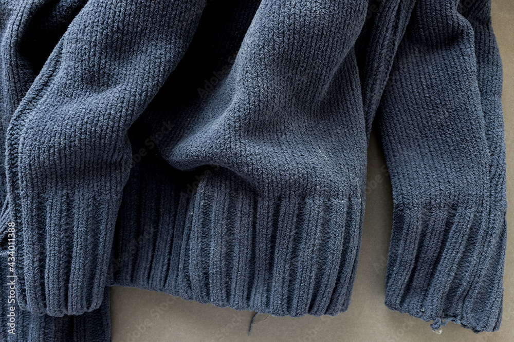 bottom part of an old navy blue zipper down sweater - photographed from above with low or raking light - emphasis on texture and folds bottom part of an old navy blue zipper down sweater - photographed from above with low or raking light - emphasis on texture and folds