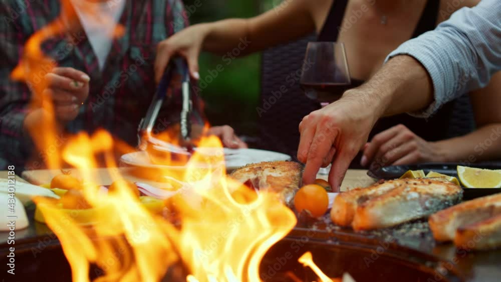 Happy fellows grilling dinner on backyard. Unknown woman cooking bbq food