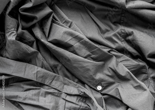 unpressed dark grey black casual dress shirt with seams - photographed from above with low or raking light - emphasis on texture and folds