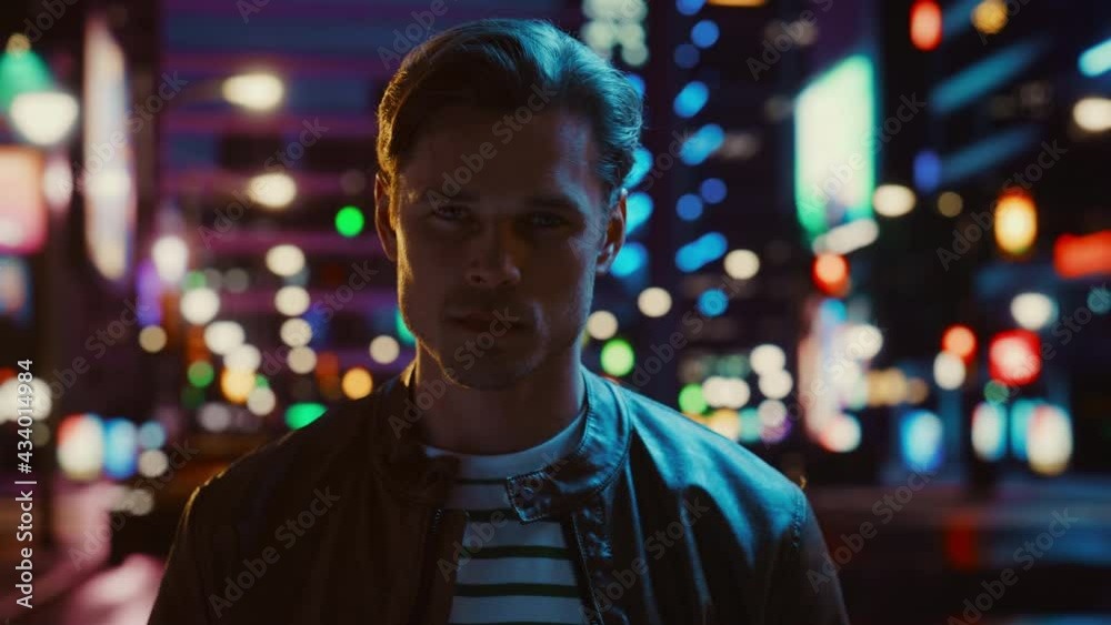 Portrait of Handsome Serious Man Turning and Looking at Camera, Standing in Night City with Bokeh Neon Street Lights in Background. Confident Young Man with Stylish Hair. Close-up Shot Portrait of Handsome Serious Man Turning and Looking at Camera, Standing in Night City with Bokeh Neon Street Lights in Background. Confident Young Man with Stylish Hair. Close-up Shot