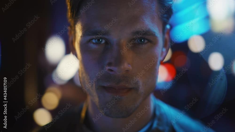 Portrait of Handsome Serious Man Standing, Turning and Looking at Camera with Night City with Bokeh Neon Street Lights. Focused Confident Intense Young Man. Close-up Shot with Cinematic Flares Portrait of Handsome Serious Man Standing, Turning and Looking at Camera with Night City with Bokeh Neon Street Lights. Focused Confident Intense Young Man. Close-up Shot with Cinematic Flares