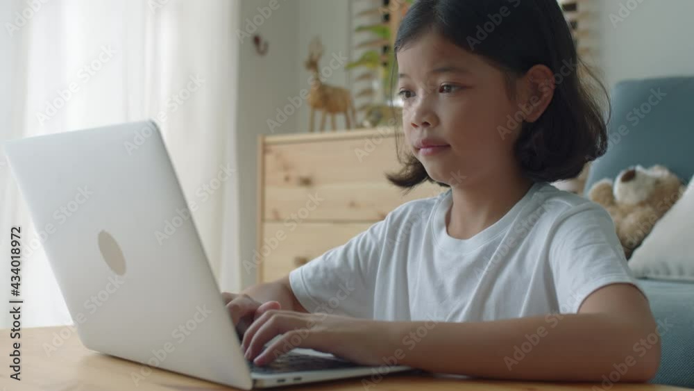 Asian little girl learning online typing work with computer laptop at home Asian little girl learning online typing work with computer laptop at home