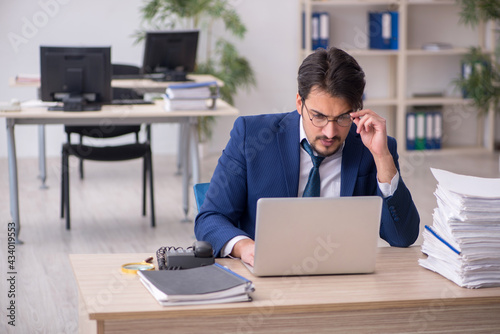 Young male employee unhappy with excessive work in the office