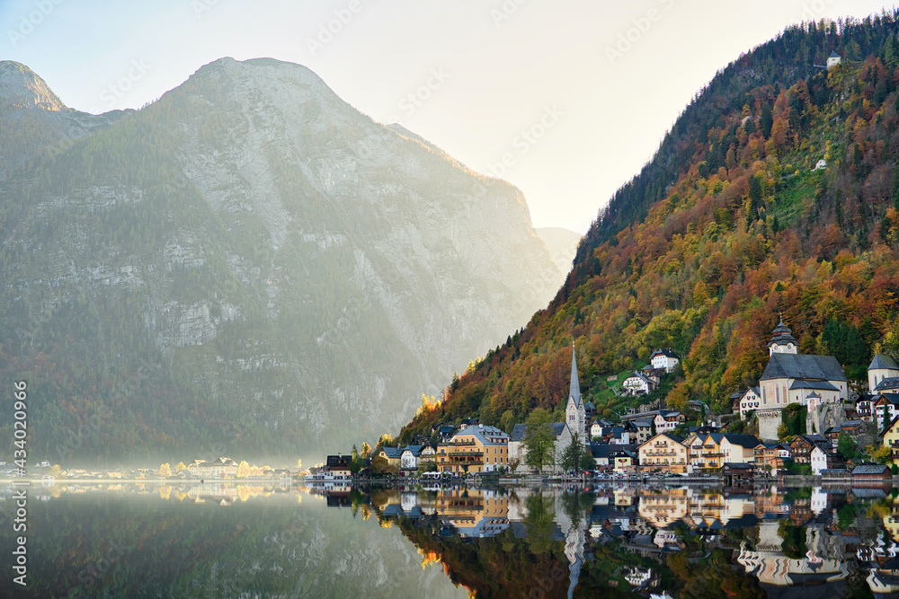 The landscape of Hallstatt, Austria, a riverside village reflecting the calm waters. The shadows in the water look like a mirror, in the evening the sunlight makes the city colorful and dreamlike.