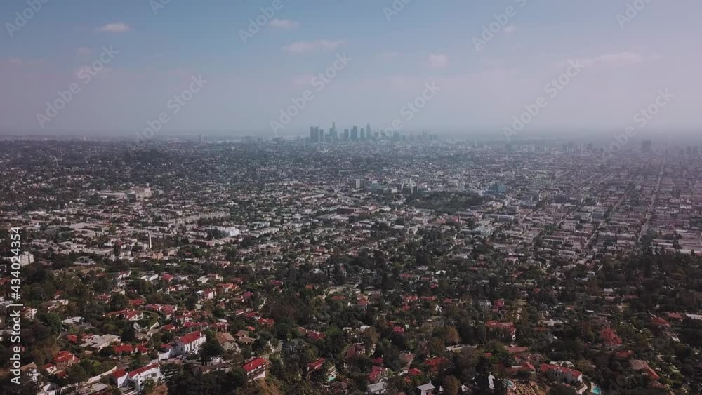 LA: Drone shot over Griffith Park looking out towards the Downtown skyline in the smog with Silverlake and Echo Park in the foreground