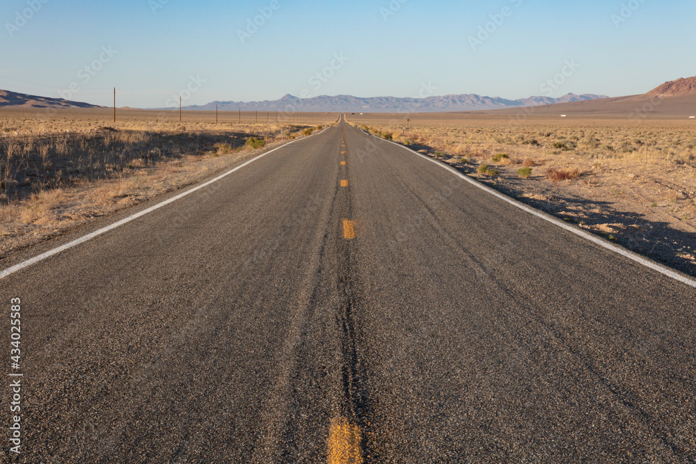 Deserted road under the Mojave Desert sun, heading straight towards the horizon Deserted road under the Mojave Desert sun, heading straight towards the horizon