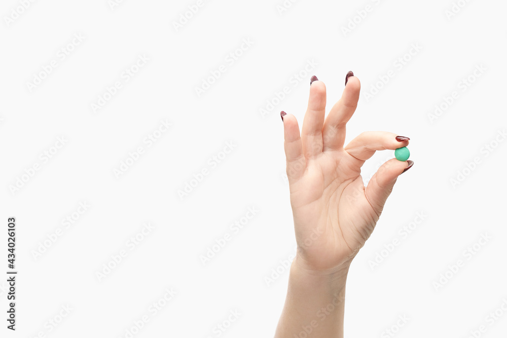 Girl holding a pill. Vitamins concept. Beautiful portrait on white background. Medicine home routine. Female morning supplement. Meds anti allergy drug Girl holding a pill. Vitamins concept. Beautiful portrait on white background. Medicine home routine. Female morning supplement. Meds anti allergy drug