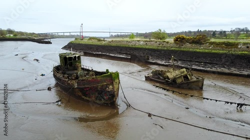 Stranded old boat wreckage off the river Clyde at Bowling harbour in Scotland. Aerial Dolly Left photo