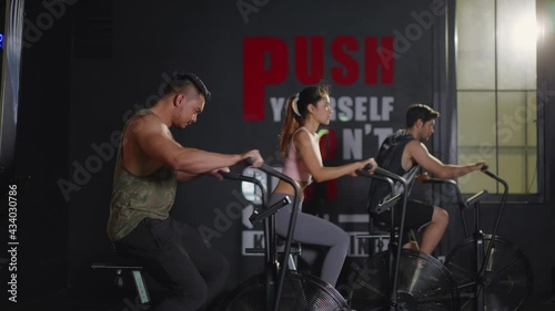 Group of multiethnic athlete spinning air bike for exercise in gym. photo