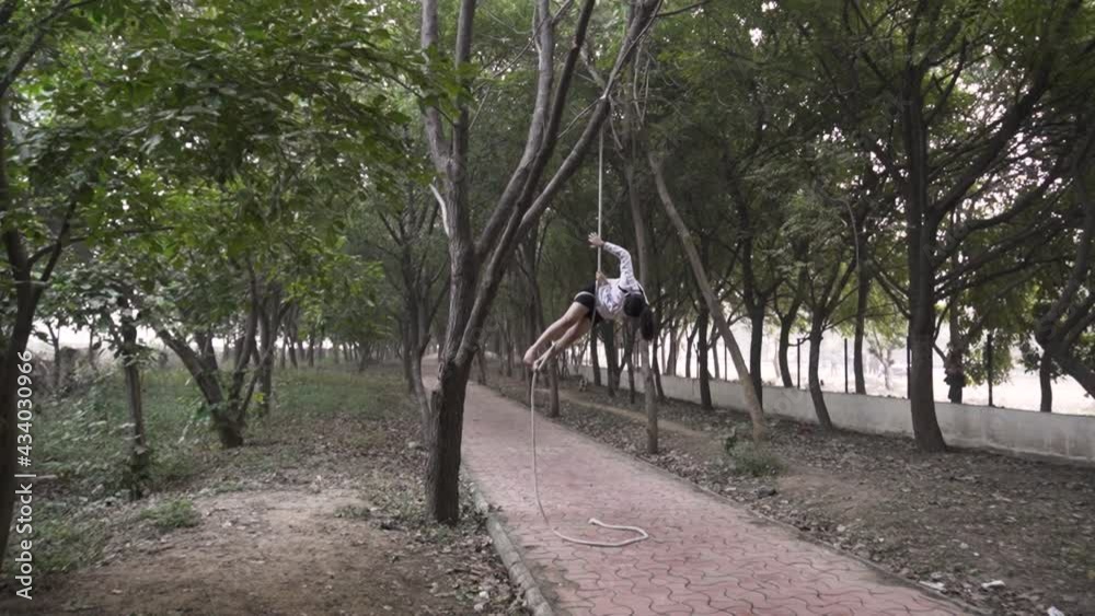 A sporty gymnast performs exercises with a rope in sportswear.Concept: power, strength, healthy lifestyle, sport. Powerful attractive muscular woman do workout with ropes in the forest A sporty gymnast performs exercises with a rope in sportswear.Concept: power, strength, healthy lifestyle, sport. Powerful attractive muscular woman do workout with ropes in the forest