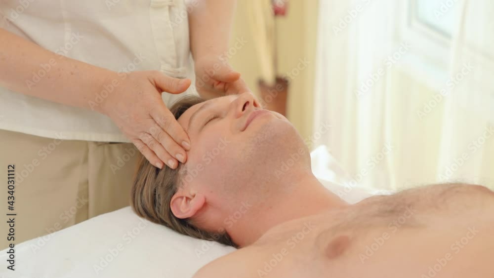 Caucasian man lying on spa bed get facial skin massage treatment with aroma essential oil skincare from female massage therapist at beauty salon. Wellness health care full body massage spa concept. Caucasian man lying on spa bed get facial skin massage treatment with aroma essential oil skincare from female massage therapist at beauty salon. Wellness health care full body massage spa concept.