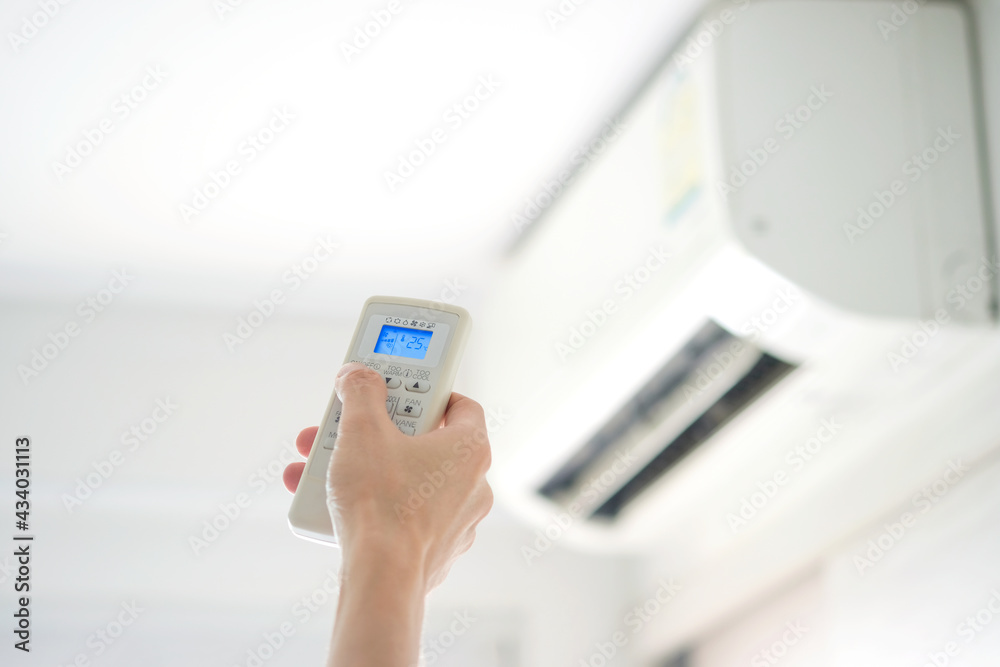 Man's hand using remote control open The air conditioner is cooled to 25 degrees Celsius in his bedroom. Health concepts and energy savings Man's hand using remote control open The air conditioner is cooled to 25 degrees Celsius in his bedroom. Health concepts and energy savings