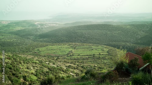 View of green hills valleys and fields in the area of the Sea of Galilee. From the hills of Amirim peaceful green landscape in seen in background. Quiet town and natural scenery in Israel photo