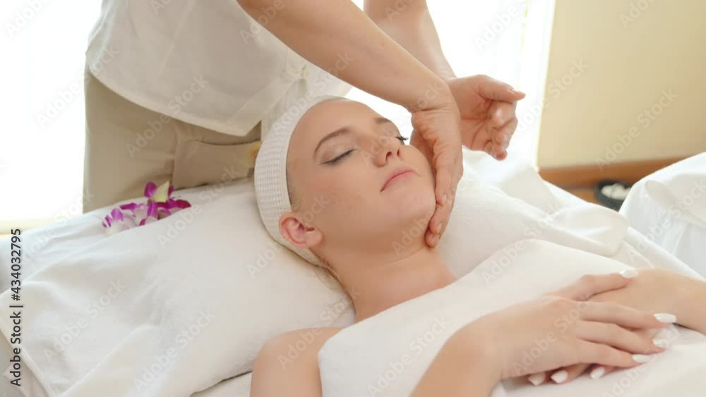 Young beautiful Caucasian woman lying on spa bed get facial massage treatment with aroma essential oil skincare from massage therapist at beauty salon. Wellness health care body massage spa concept. Young beautiful Caucasian woman lying on spa bed get facial massage treatment with aroma essential oil skincare from massage therapist at beauty salon. Wellness health care body massage spa concept.