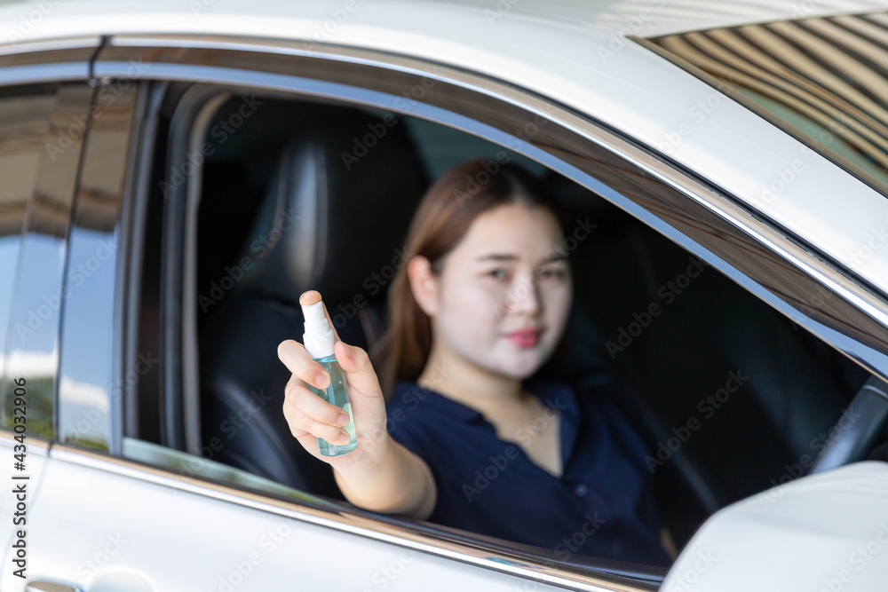 Girl sitting in a private car Use the hand to hold the bottle of alcohol spray and spray it up. Prevent the coronavirus