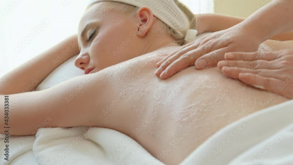Caucasian woman lying on spa bed get back massage treatment scrub skincare with spa salt and essential oil from female massage therapist at beauty salon. Wellness health care body massage spa concept. Caucasian woman lying on spa bed get back massage treatment scrub skincare with spa salt and essential oil from female massage therapist at beauty salon. Wellness health care body massage spa concept.