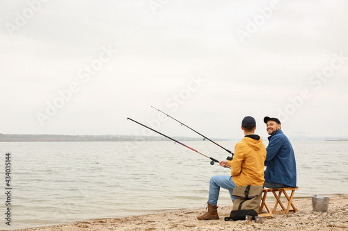 Father and son fishing together on river