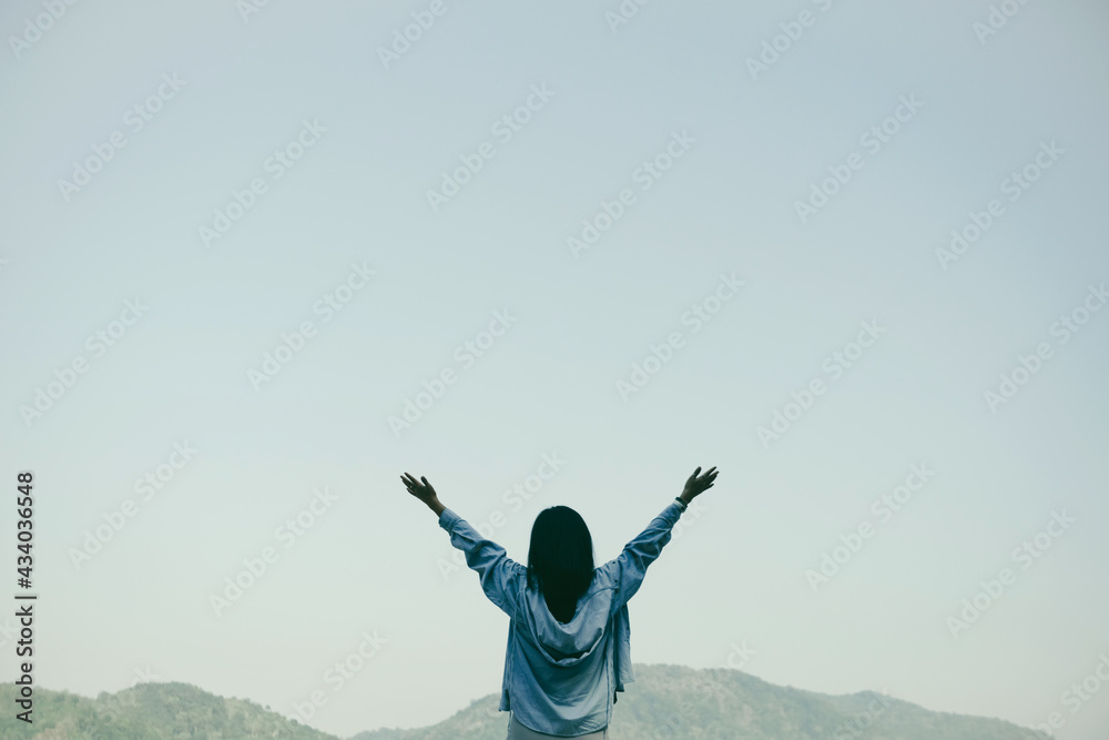 Woman rise hands up to sky freedom concept with blue sky and summer mountain background