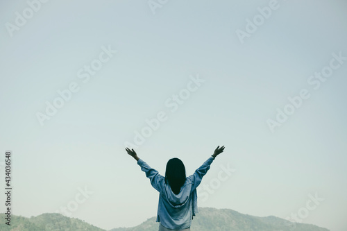 Woman rise hands up to sky freedom concept with blue sky and summer mountain background