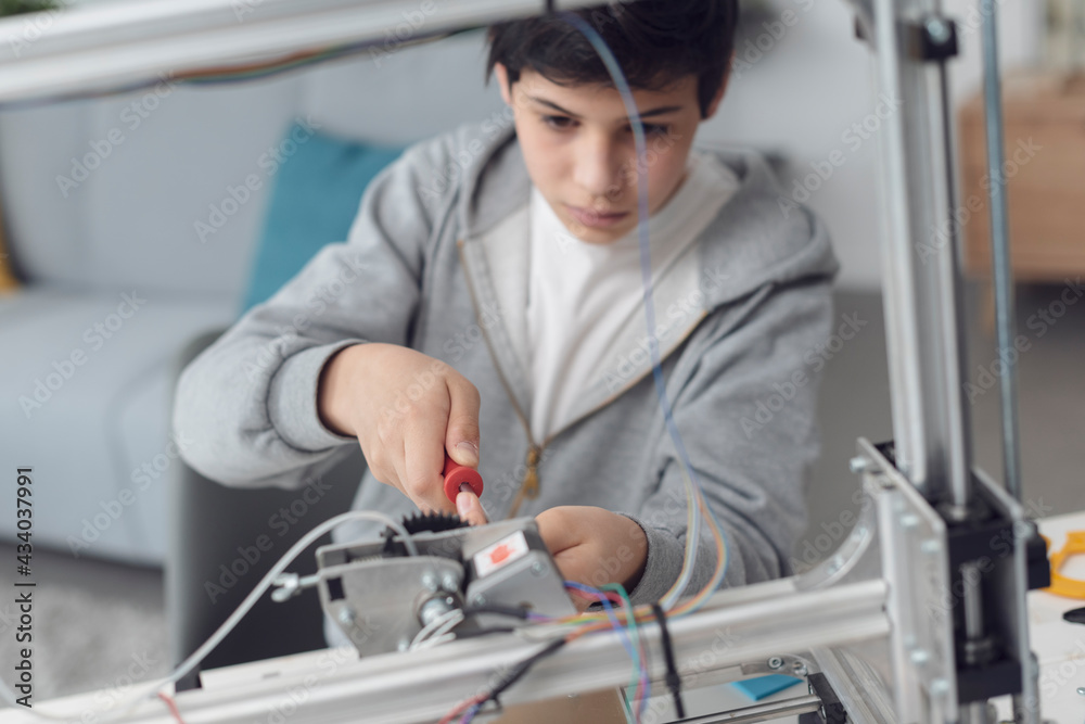 Smart boy using a 3D printer at home Smart boy using a 3D printer at home