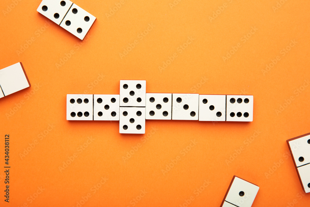 Playing dominoes on a orange table. Domino effect Playing dominoes on a orange table. Domino effect