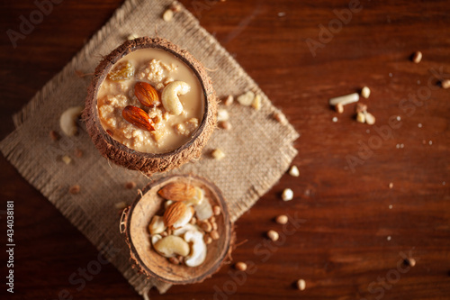 Close-up of Creamy Sabudana Kheer Garnished with dry fruits. Indian delicious dessert. Served in the coconut shell. Front view on wooden background.