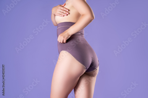 Half naked woman in high-waisted corrective panties, sexy female body in shapewear on purple background