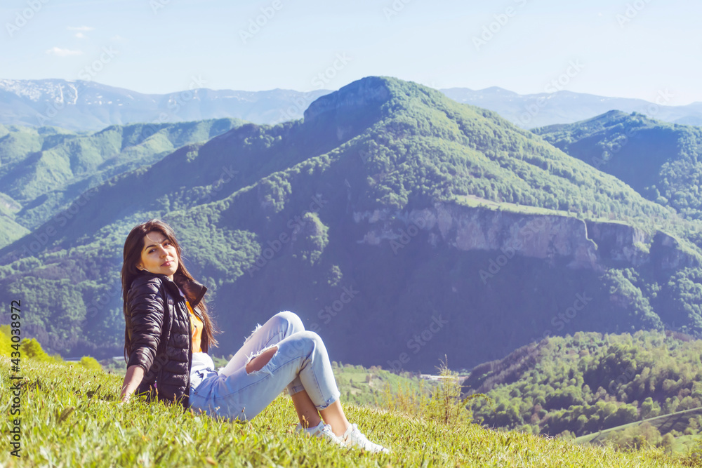 Young Woman Sitting on a Green Meadow in the Summer Mountain with Stunning View .
Balkan Mountains ,Bulgaria   