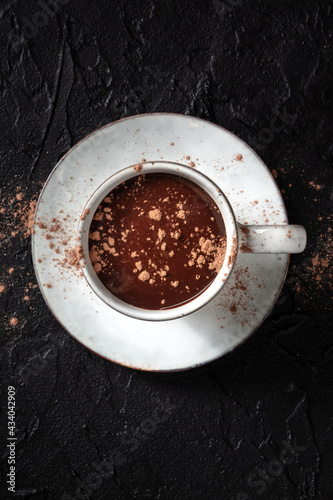Hot chocolate with chocolate powder, top shot on a black background with copy space