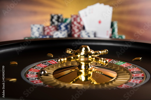 Poker Chips on gaming table  roulette wheel in motion  casino background